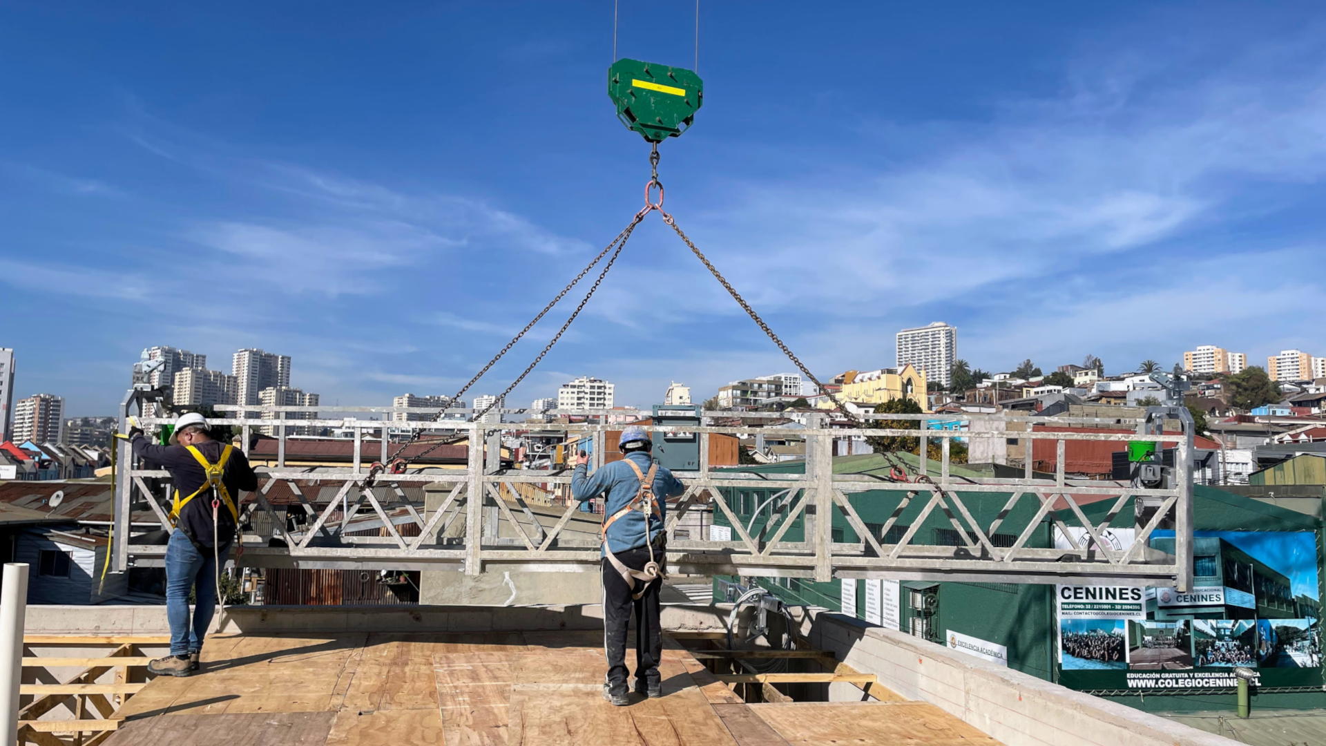 Andamios colgantes y maquinaria de MacUP en una obra de construcción al atardecer.
